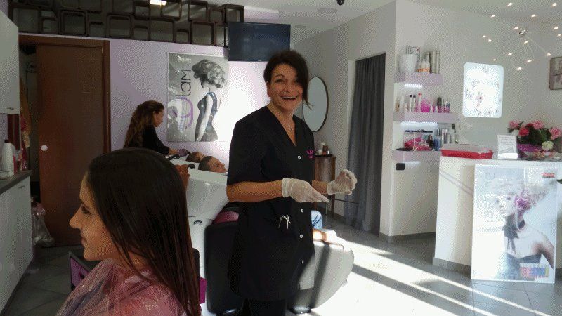 Una parrucchiera sorride mentre lavora su una cliente in salone
